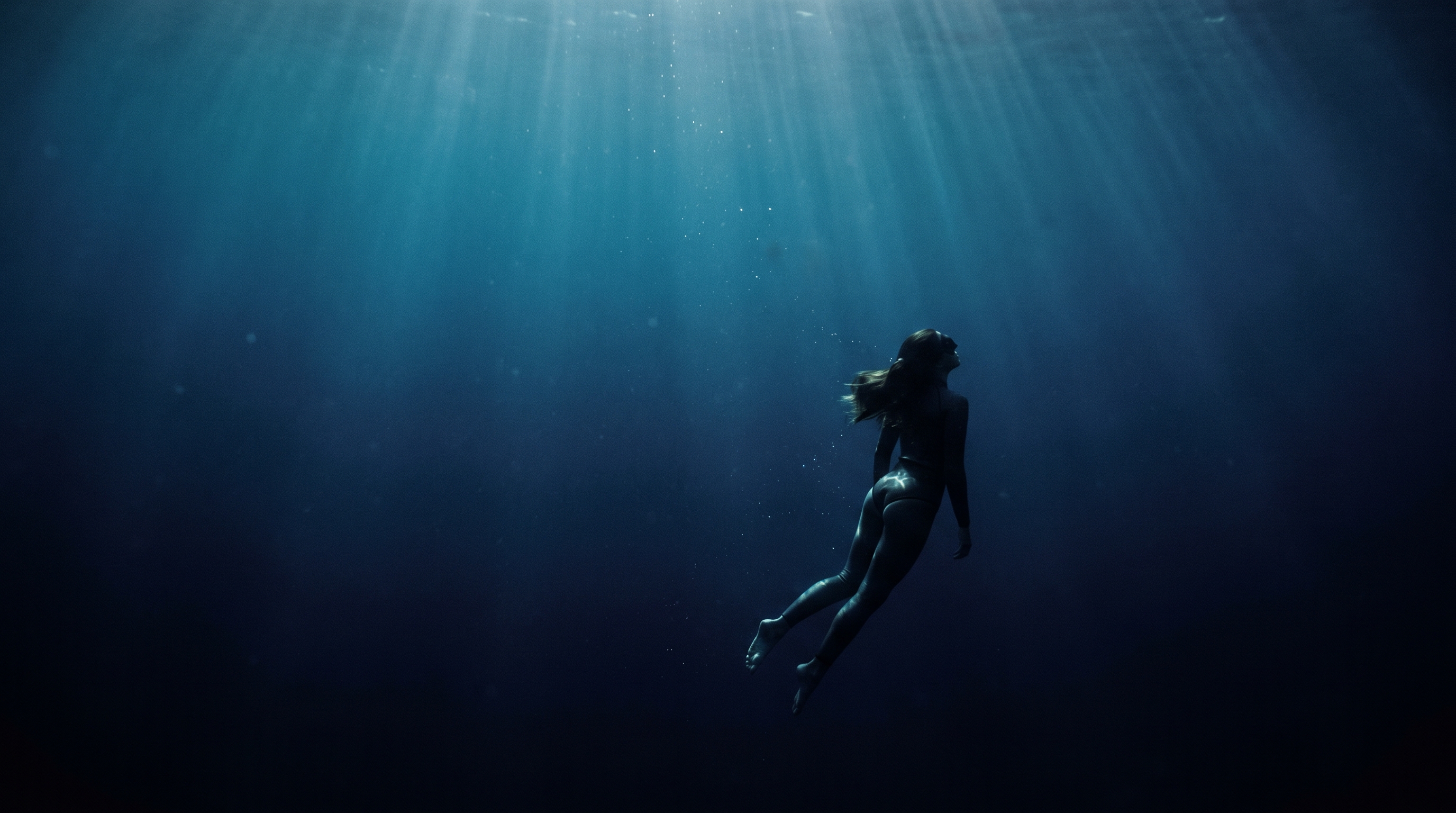 Diver descending into deep blue water